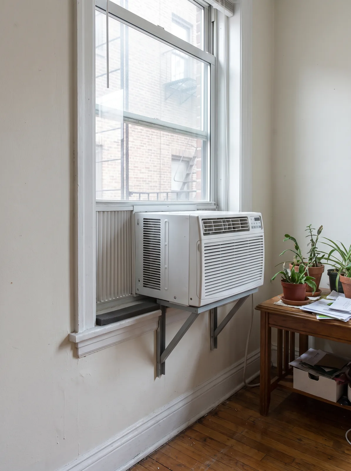Window air conditioner seated on a support bracket with the sash closed on it