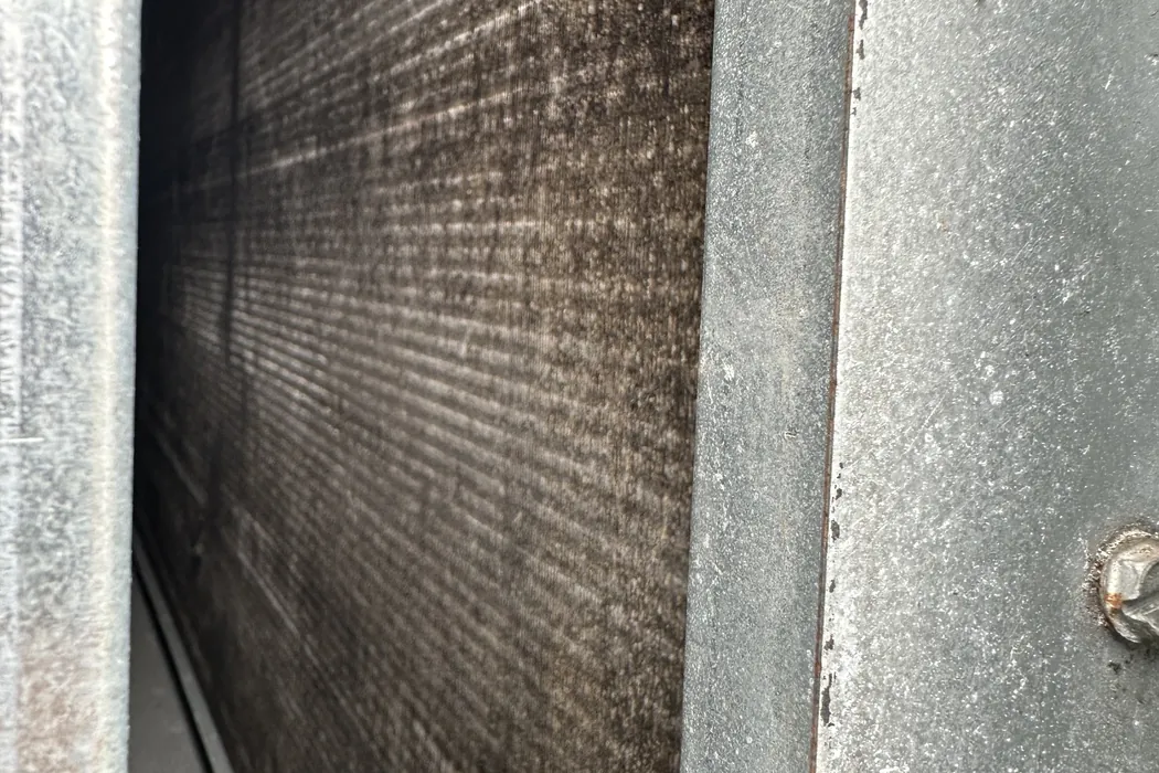 Evaporator coil dark with dust inside an air handler cabinet
