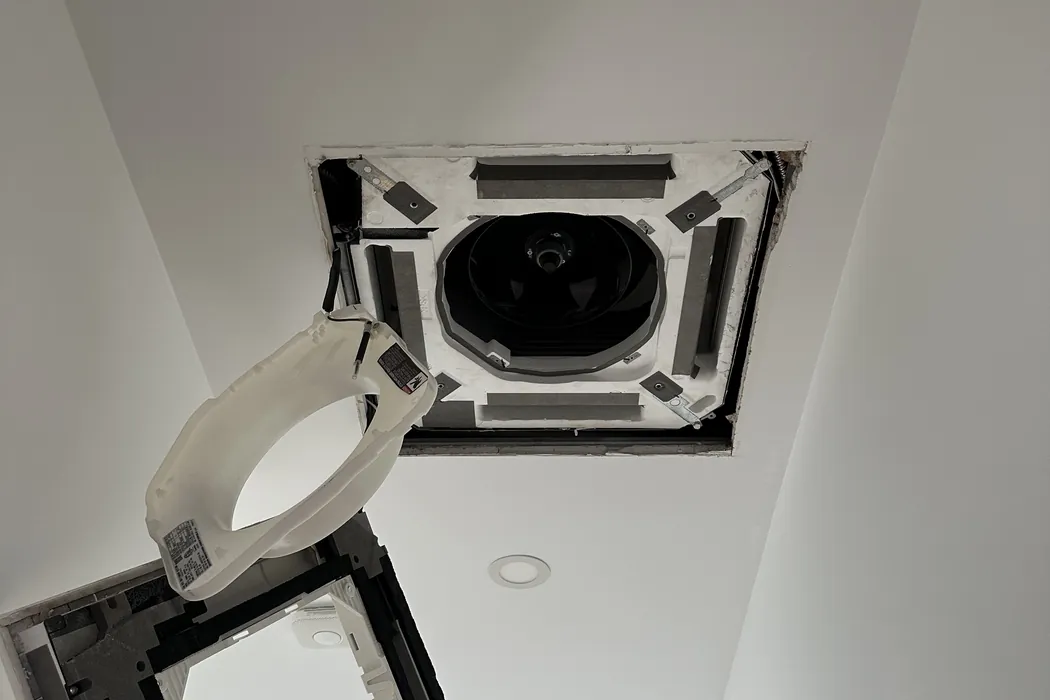 Ceiling cassette with its centre panel hanging open below the ceiling