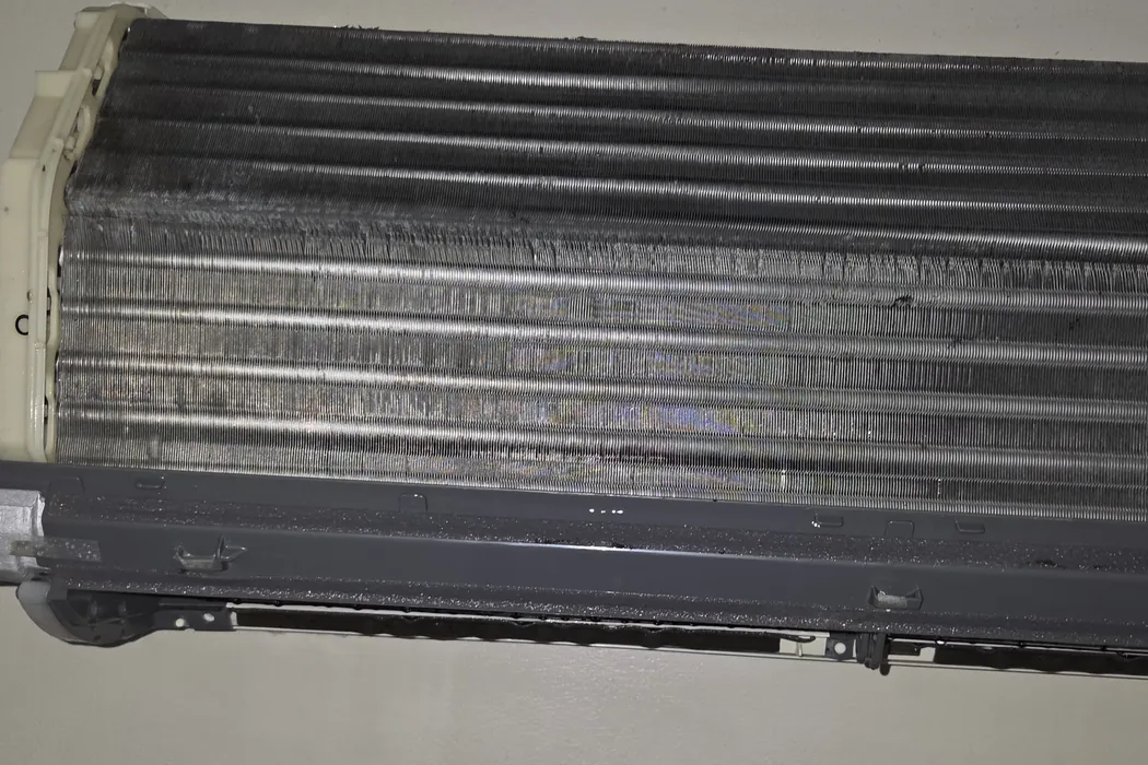 The same mini-split coil rinsed clean, bare aluminum fins