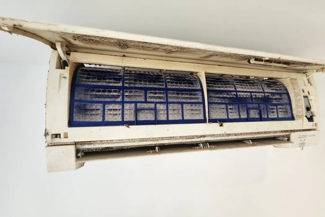 Open mini-split panel showing dust-loaded filters