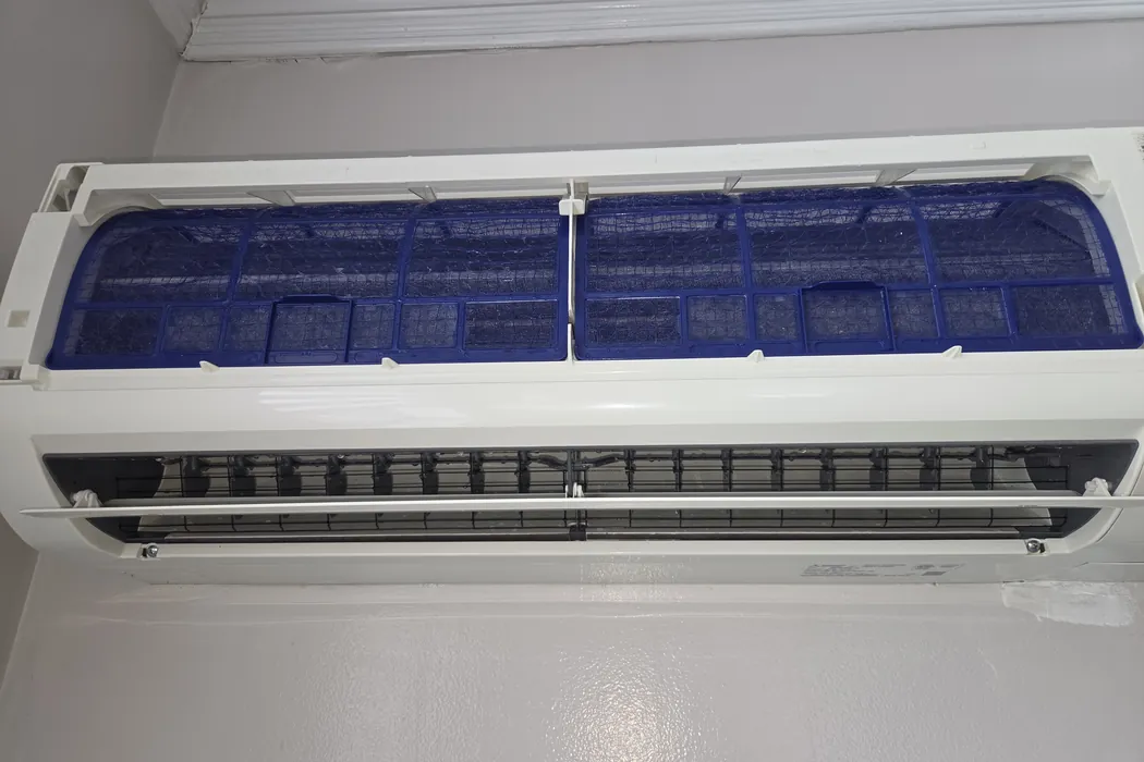 Mini-split head reassembled with clean filters behind the open panel